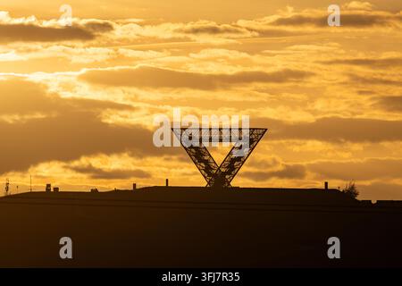 Silhouette du monument Saarpolygon sur un terril sous un ciel doré dramatique au coucher du soleil, Sarre, Allemagne Banque D'Images