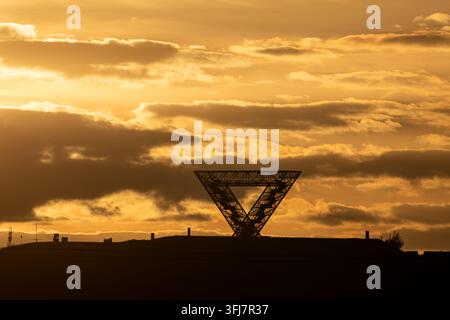 Silhouette du monument Saarpolygon sur un terril sous un ciel doré dramatique au coucher du soleil, Sarre, Allemagne Banque D'Images