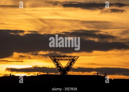 Silhouette du monument Saarpolygon sur un terril sous un ciel doré dramatique au coucher du soleil, Sarre, Allemagne Banque D'Images