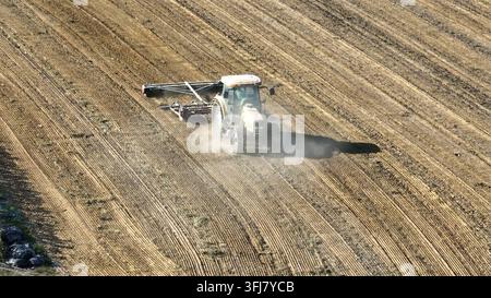 Plan aérien d'approche d'un tracteur travaillant dans un champ agricole, cultivant et labourant un sol sec. Concept d'agrobusiness. Concept de petite exploitation agricole à Ame Banque D'Images