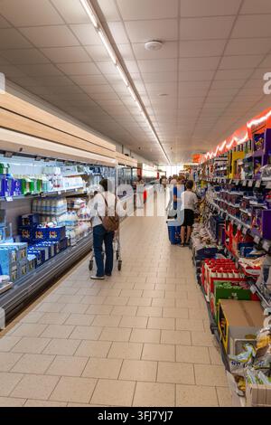 Des gens avec des chariots de courses dans un rayon de supermarché animé, regardant les étagères de produits d'épicerie remplies dans Lidl, Bucarest, Roumanie Banque D'Images