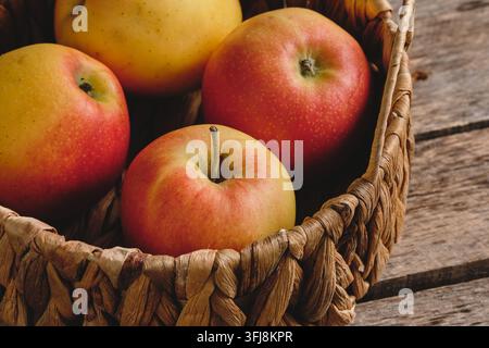 Composition en gros plan de pommes fraîches rouges et jaunes dans un panier sur du bois Banque D'Images