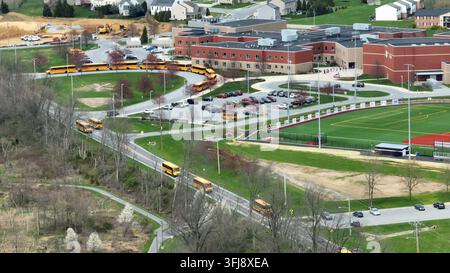 Conduite de bus scolaires jaunes sur la route devant une école américaine. Journée ensoleillée dans une ville américaine. Transport pour les élèves et les étudiants aux États-Unis. Vue aérienne, Ma Banque D'Images