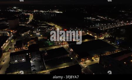 Vue nocturne de la ville avec circulation sur la rue principale dans une ville historique. Paysage urbain illuminé avec magasins et restaurants. Pont en arrière-plan. Vue aérienne par le dessus Banque D'Images