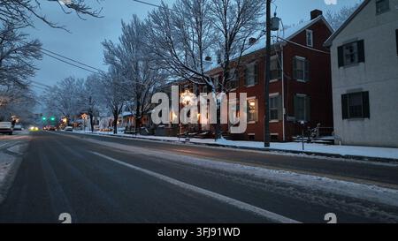 Prise de vue en contre-plongé d'une rue glacée et boueuse après une chute de neige dans une ville américaine. Rues et boutiques décorées le long de la rue du centre-ville de Lititz, PA. Arbres sans feuilles Banque D'Images