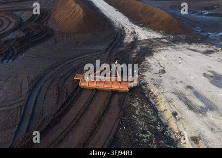 Vue aérienne par drone d'un attachement industriel lourd pour le ridage de la tourbe posé sur un champ d'extraction de tourbe en Estonie. Banque D'Images