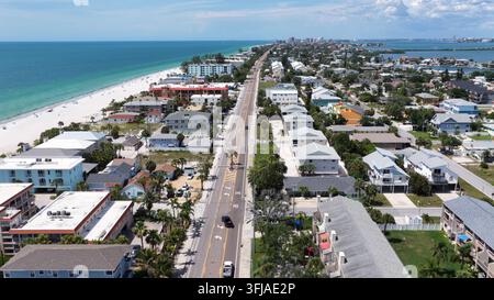 La route côtière passe entre les appartements en bord de mer et les eaux turquoise du golfe à Indian Rocks Beach, en Floride, les voitures roulent devant une plage de sable blanc près de C lointain Banque D'Images