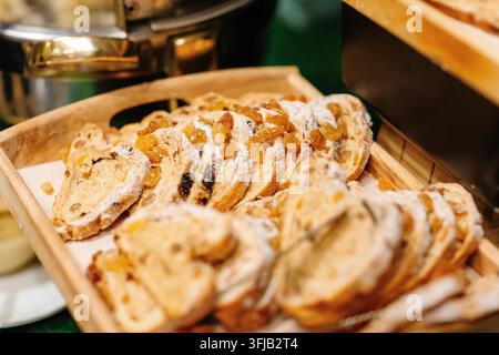 Pain aux fruits tranché avec raisins secs et sucre en poudre sur un plateau en bois à un buffet Banque D'Images