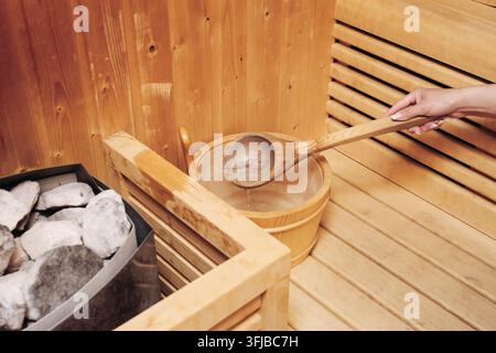 Louche en bois et seau à côté de pierres chaudes dans un sauna traditionnel. Fond bien-être pour la thérapie par la chaleur relaxante, les bains de spa et le sauna finlandais. Banque D'Images