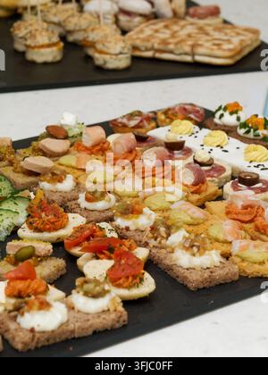 Assortiment de canapés salés et de sandwichs ouverts disposés sur des plateaux de traiteur lors d'une réception Banque D'Images