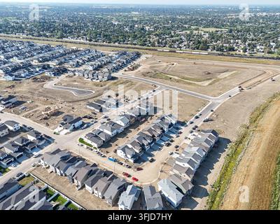 Vue aérienne du quartier de Brighton à Saskatoon, montrant des maisons neuves aux toits gris. Des routes et des terrains en friche s'étendent à travers le paysage. Arbres Banque D'Images