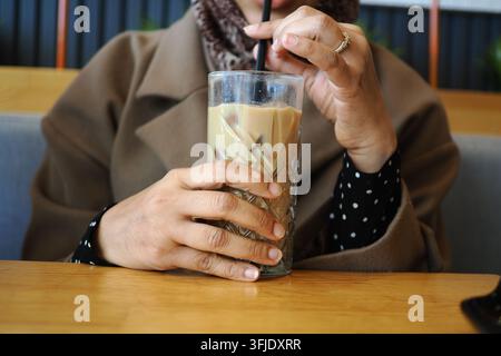 une femme buvant de la glace tard dans un café tout en étant assise . Banque D'Images