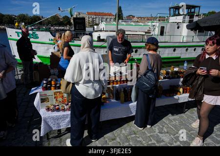 Les clients parcourent des pots de confiture, de miel et d'autres conserves à un stand à côté d'un bateau amarré à Náplavka. Banque D'Images