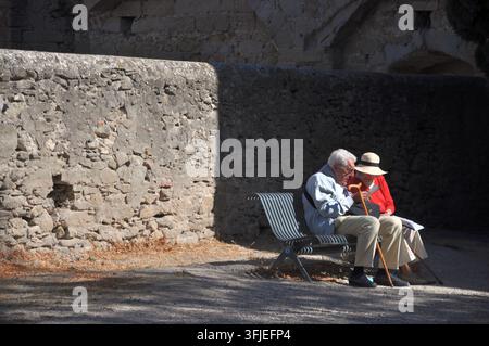 CARCASSONNE, FRANCE - 3 OCTOBRE 2016 : Un homme et une femme âgés sont assis ensemble sur un banc à côté d'un mur de pierre à Carcassonne. Banque D'Images
