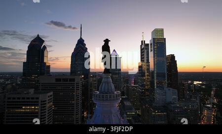 Statue de William Penn au sommet de la tour de l’hôtel de ville de la ville de Philadelphie. Plan large en montant en hauteur. Temps de coucher de soleil douillet. One Liberty Place et Comcast Technologie Banque D'Images