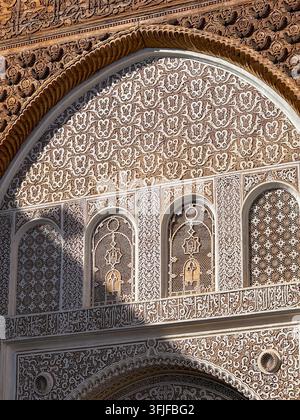 Close-up des motifs géométriques et calligraphiques ornés sur la façade de la Madrasa Ben Youssef à Marrakesh, Maroc, sous un soleil éclatant. Banque D'Images