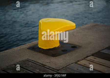 Pilon d'amarrage jaune vif sur une jetée en béton, infrastructure maritime, sécurité d'amarrage, équipement portuaire, industrie des voyages nautiques Banque D'Images