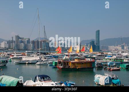 Bateau de jonque chinois traditionnel coloré avec des voiles vives parmi les yachts de luxe et les bateaux de pêche au refuge contre les typhon de Causeway Bay à Hong Kong Banque D'Images