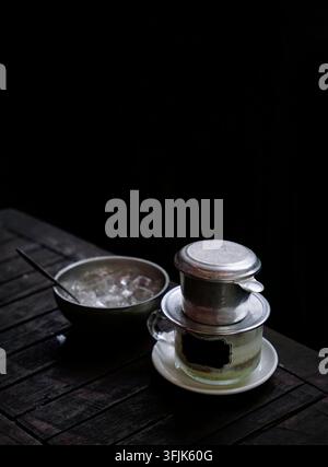 Verre de filtre à café salé servi avec un bol de glace sur une table en bois Banque D'Images