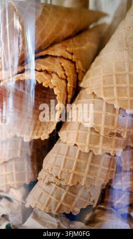 Cones de glace gaufrés croustillants vides empilés dans un bocal en verre transparent. Cônes de gaufres dorés au four prêts à servir du gelato ou des desserts d'été sucrés. Banque D'Images