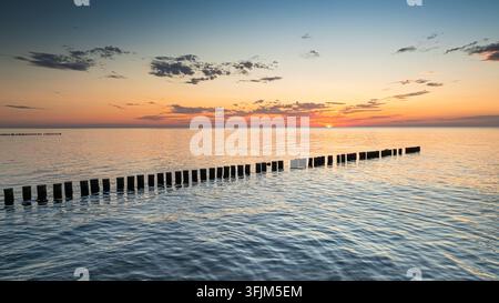 Brise-lames de la mer Baltique brillant sous un coucher de soleil calme en Pologne en été. Vue aérienne de la mer Baltique après une tempête. Banque D'Images