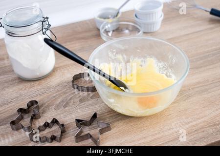 Pâte à biscuits de Noël avec emporte-pièces festifs sur une table en bois dans la cuisine moderne Banque D'Images