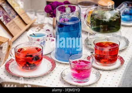 Théière en verre et tasses avec différents types de thé à base de plantes sur la table d'un marché de rue Banque D'Images