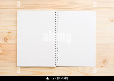 Vue de dessus d'un modèle de cahier à spirale ouvert avec des pages lignées et vierges sur un fond en bois clair avec espace de copie Banque D'Images
