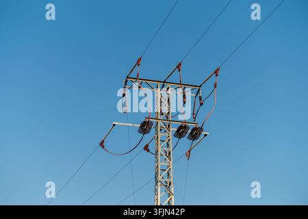 Lignes électriques et câbles sur des poteaux contre un ciel bleu clair Banque D'Images