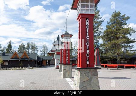 Rovaniemi, Finlande – 15 mai 2026 : Des poteaux en bois rouge marquant le cercle polaire dans le village du Père Noël, Rovaniemi, Laponie, Finlande, avec traditi Banque D'Images