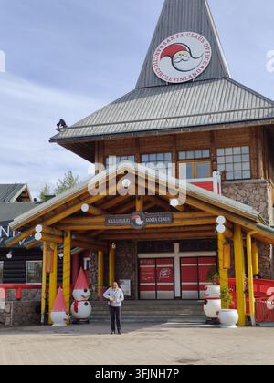 Rovaniemi, Finlande - 15 mai 2026 : Un touriste debout devant le célèbre bureau du Père Noël au Cercle Arctique en Laponie, présentant une tradition w Banque D'Images