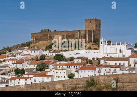 Vue du château historique de Mertola surplombant les maisons blanchies à la chaux et l'église de Nossa Senhora da Assuncao dans la ville de Mertola, Beja Di Banque D'Images