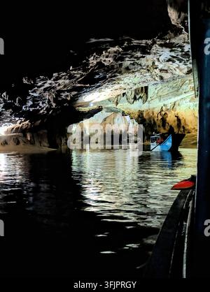 PHONG NHA, VIETNAM - 18 MARS 2026 : Bateau touristique bleu marqué PHONG NHA CAVE naviguant à travers la caverne brillamment éclairée remplie de stalactites suspendues Banque D'Images