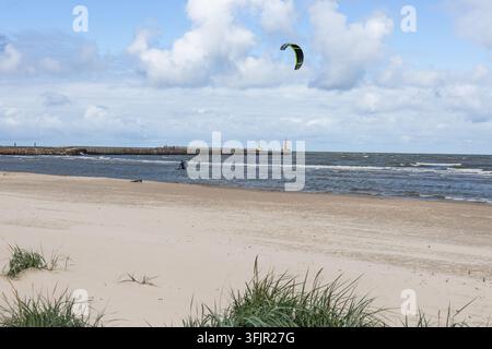 Kitesurfeur glissant sur les vagues de la mer Baltique près d'une plage de sable Banque D'Images