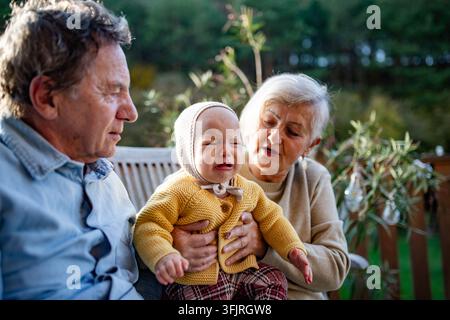 Grands-parents tenant bébé dans l'étreinte chaude pendant la saison d'automne. Banque D'Images