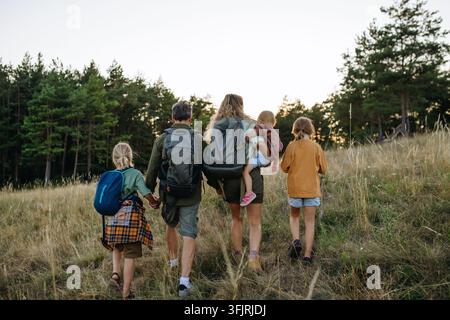 Vue arrière d'une famille de randonneurs sur une prairie lors d'un voyage de camping automnal. Banque D'Images