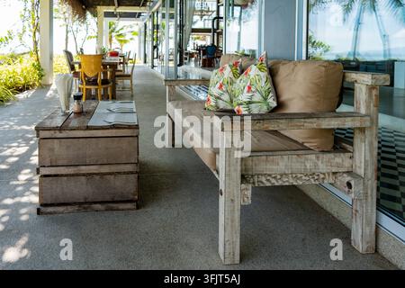 Canapé en bois rustique avec coussins tropicaux sur la terrasse. Lounge extérieure confortable sur la terrasse avec banc en bois rustique fabriqué à la main avec coussins et Pri tropical Banque D'Images