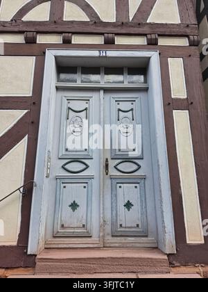 Belle porte double ornée de sculptures décoratives et de panneaux ovales sur une maison traditionnelle à colombages. Bois peint en bleu clair historique Banque D'Images