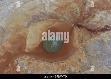 Une vue aérienne encadre l'œil minéral vert d'Aiken Spring au sein de cercles rouges et orange audacieux. Le motif surréaliste donne une impression d'un autre monde. Banque D'Images