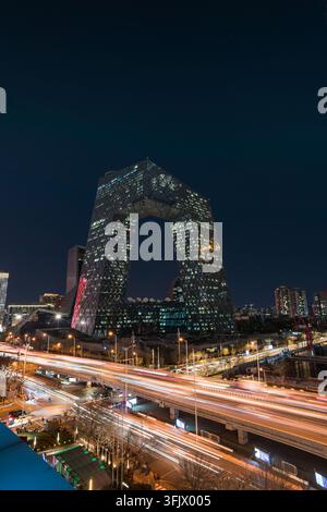 Vue nocturne du siège de CCTV à Pékin avec des routes urbaines vibrantes et traînées de lumière Banque D'Images