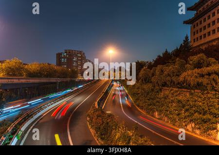 Traînées de lumière du trafic sur les routes urbaines la nuit dans la vieille ville de Pékin Banque D'Images