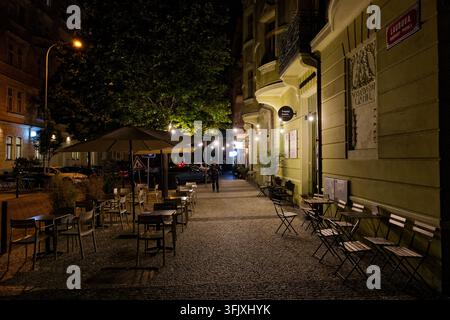 Sièges extérieurs d'un café et piétons sur la rue Laubova à Vinohrady la nuit. Banque D'Images