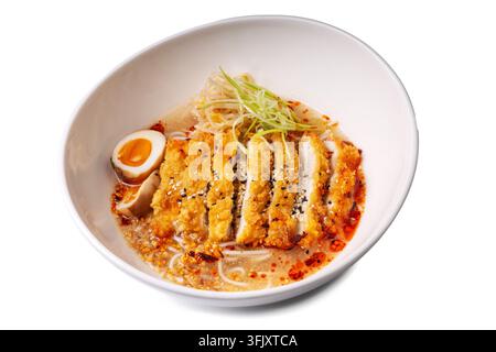 Délicieuse soupe de nouilles ramen japonaise avec du poulet katsu croustillant, un œuf mollet et de l'huile de piment épicée dans un bol blanc, isolé sur blanc Banque D'Images