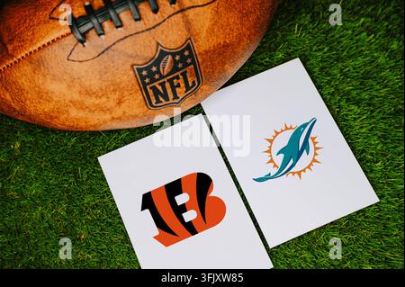 OHIO, ÉTATS-UNIS, 7 SEPTEMBRE 2026 : Concept de match NFL Cincinnati Bengals vs Miami Dolphins avec logos des équipes imprimés sur du papier blanc à côté d'un pied en cuir Banque D'Images