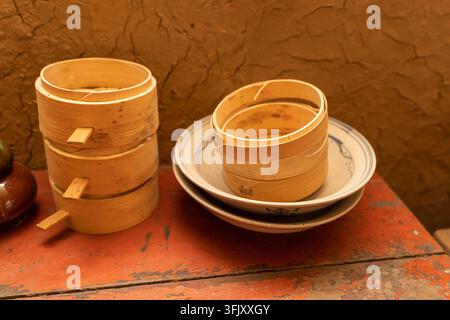 Steamer en bambou sur une vieille table en bois avec de la peinture rouge Banque D'Images