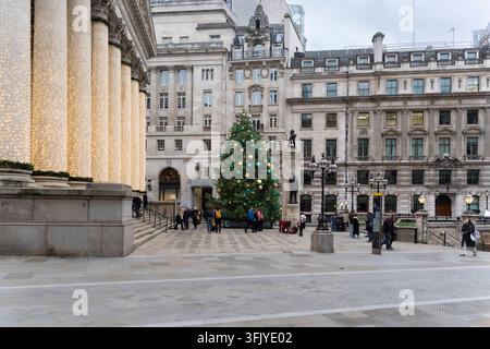 Les gens profitent de l'ambiance des fêtes autour d'un sapin de Noël géant et de piliers illuminés à l'extérieur de la Royal Exchange à Londres. Banque D'Images