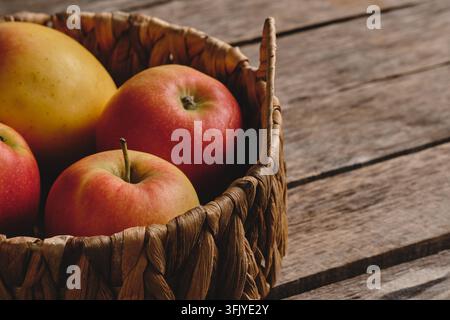 Prise de vue détaillée de pommes juteuses mûres dans un panier rustique sur fond en bois Banque D'Images