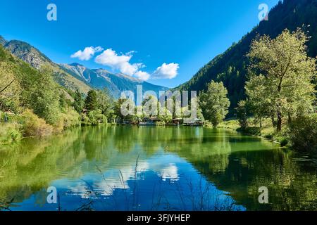 Lac de montagne paisible à Isola, France, avec des reflets clairs, des arbres verts et un ciel bleu dans le paysage estival Banque D'Images