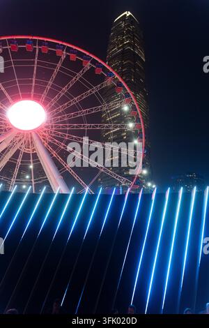 Les gens profitent des vues nocturnes sur la grande roue d'observation de Hong Kong et la tour Two IFC depuis le front de mer de Central pour des loisirs. Banque D'Images