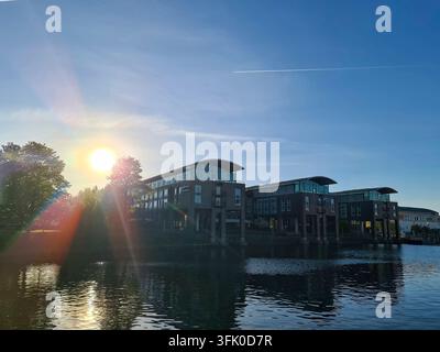 Luebeck, Allemagne - 01. Mai 2026 : bâtiments modernes reflétant dans l'eau calme sous un ciel lumineux de coucher de soleil Banque D'Images